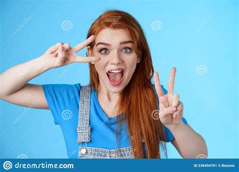 cute excited redhead enthusiastic girl smiling look joyful show peace victory signs near face