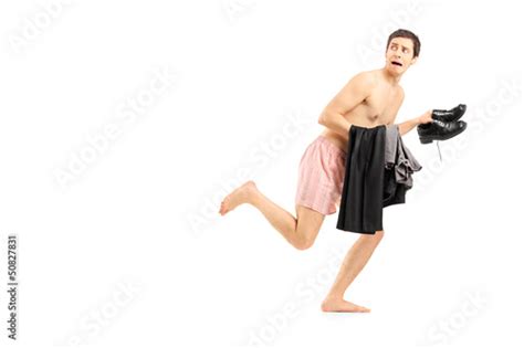 An Embarrassed Naked Man In Underwear Holding His Clothes And Ru Stock