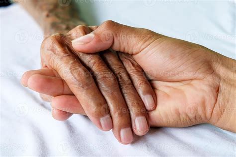 Hands Of The Old Man And A Man Hand On The White Bed 7009976 Stock