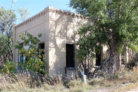 An Old Building Sitting In The Middle Of A Field Next To Some Trees And