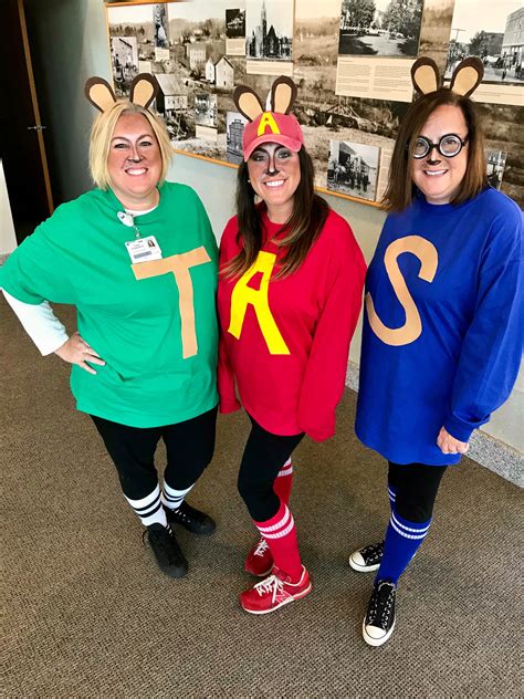Three Women Dressed Up In Costumes Standing Next To Each Other On The