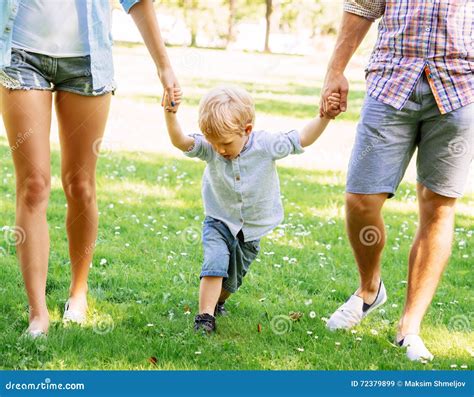 Handsome Toddler Having A Walk With Parents Holding Their Hands Stock