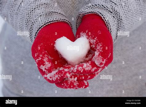 Red Gloves Holding A Heart Made From Snow Stock Photo Alamy