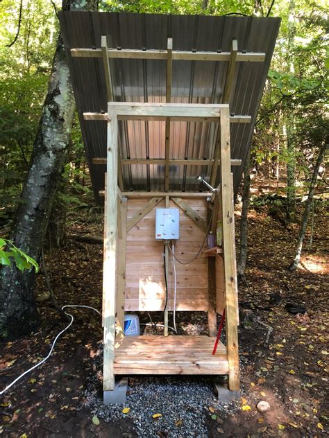A Small Outhouse In The Woods With An Electrical Outlet On It S Side