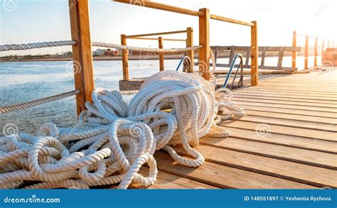 Closeup Photo Of Ropes Lying On The Wooden Deck Of Long Pier At Sea