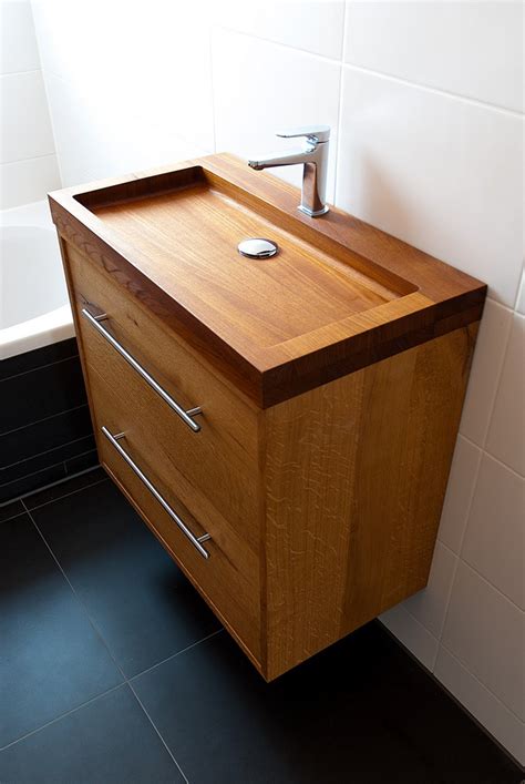 The wooden vanity countertop runs straight on as bathtub panelling and continues all the way up the wall behind the wet areas. Fascinating Wooden Bathroom Sinks to Create a Classic Style