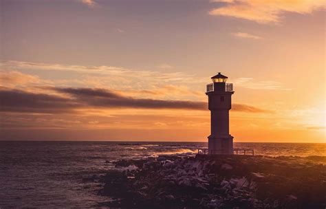 Beacon White Lighthouse Tower Under Yellow And White Cloudy Skies At