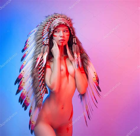 Fotos de Mujer desnuda en traje nativo americano con plumas sobre un fondo de neón Imagen de