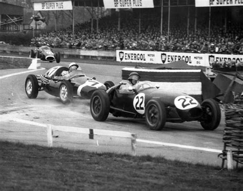 An Old Photo Of Two Race Cars Racing On The Track In Front Of A Crowd