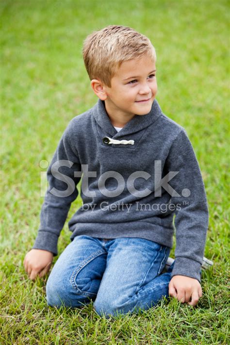 Little Boy Kneeling On Grass Stock Photos