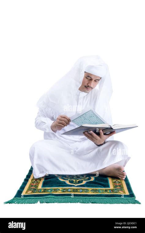 Arab Muslim Man Sitting And Reading The Quran On The Prayer Rug