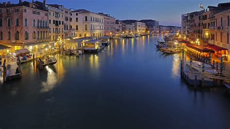 River Between Buildings And Boats With Lights On River In Italy Venice
