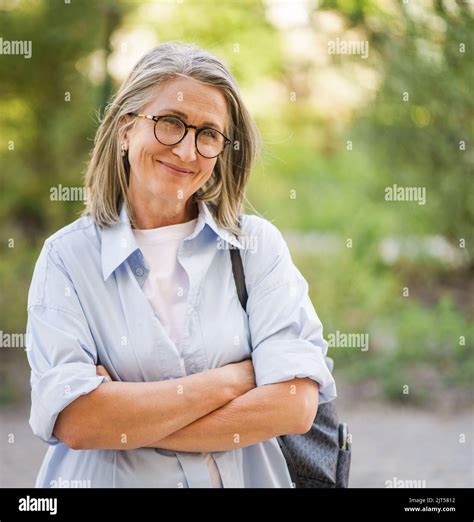 Beautiful Grey Hair Mature Woman Wearing Glasses And Backpack Standing Arms Folded Outdoor