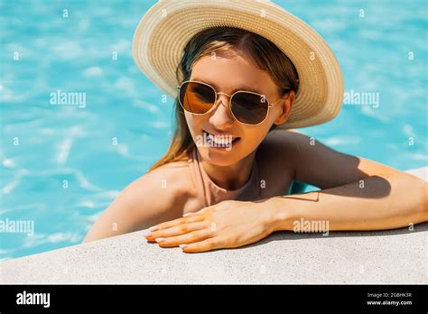 Beautiful Young Tanned Woman In Sunglasses And Summer Hat In The Outdoor Pool Woman In A