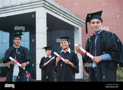 Graduate Students Holding Diplomas And Smiling In University Campus
