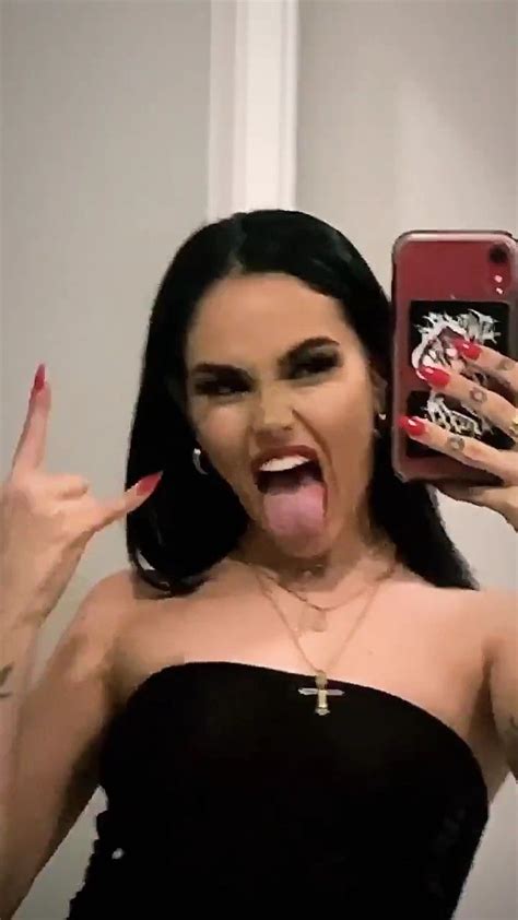 A Woman With Her Tongue Out Holding Up A Cell Phone