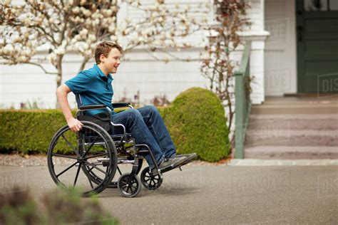 Teenage Boy Pushing Himself In A Wheelchair Stock Photo Dissolve