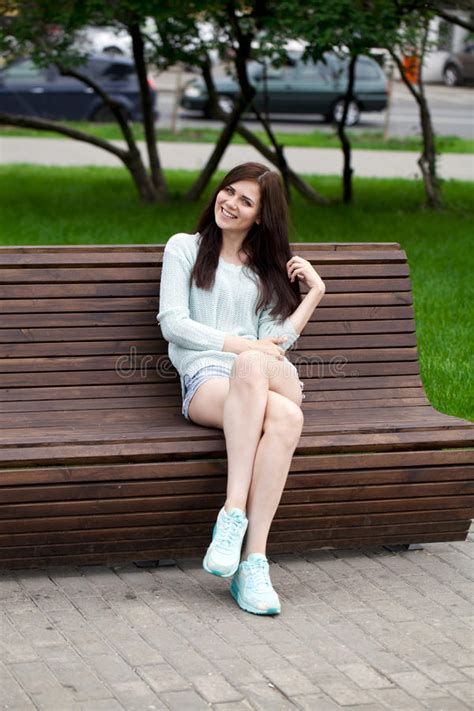 Young Beautiful Girl Sitting On A Bench In The Summer Park Stock Photo