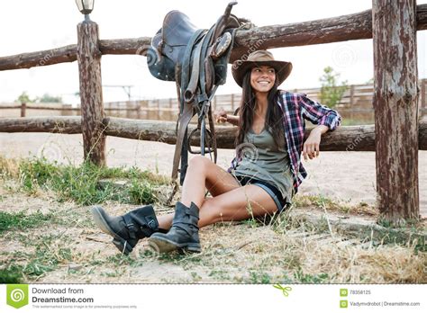 Smiling Happy Cowgirl Sitting And Resting At The Ranch Fence Stock
