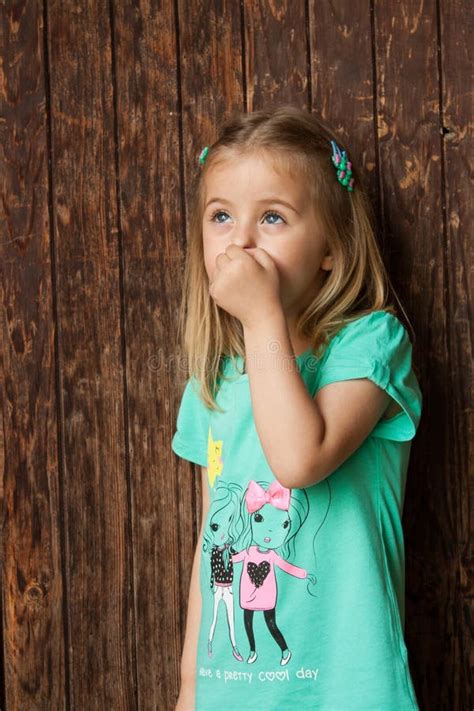 Outdoor Portrait Of A Cute Little Girl Standing Next Wooden Door Stock