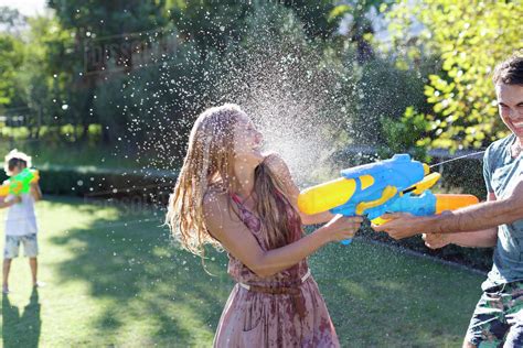 Couple Playing With Water Guns In Backyard Stock Photo Dissolve