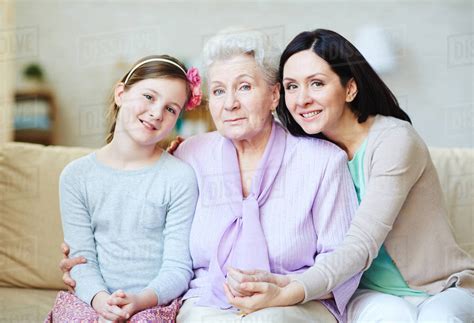 Grandmother With Her Daughter And Granddaughter Sitting On A Couch