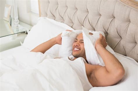 Premium Photo Sleepy Man Covering Ears With Pillow In Bed