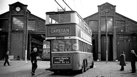 A Double Decker Bus Parked In Front Of A Building With People Walking