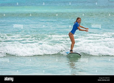 Young Woman Learns To Surf On A Long Board On Learner Waves In A