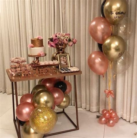 A Table Topped With Lots Of Pink And Gold Balloons
