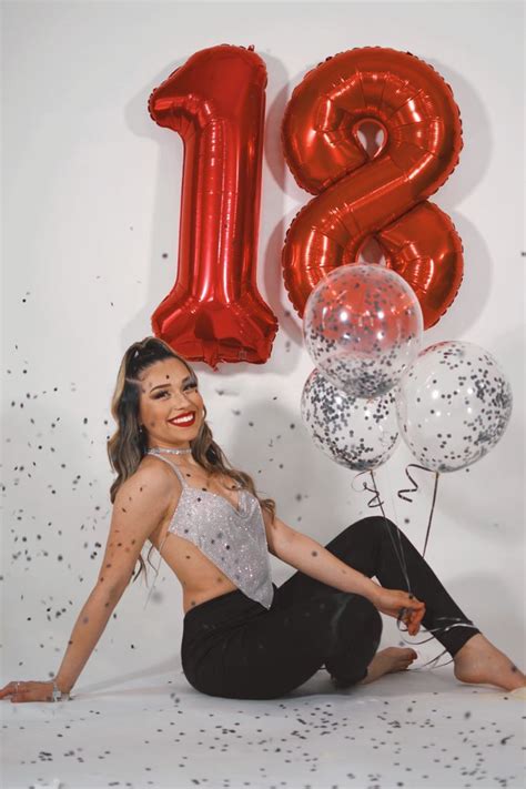 A Woman Is Sitting On The Floor With Balloons And Confetti In Front Of Her