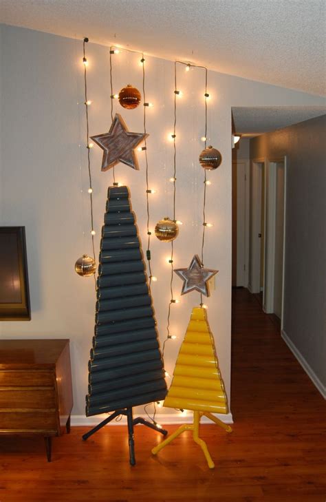 A Christmas Tree With Lights Hanging From It S Sides In Front Of A Wall