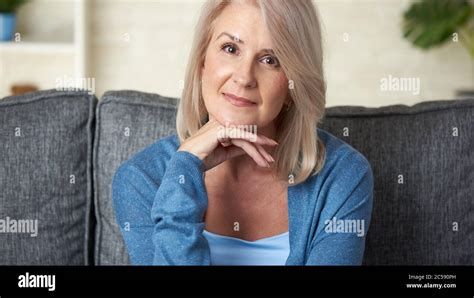 portrait de la belle femme blonde de 50 ans est assise sur un canapé à la maison photo stock alamy