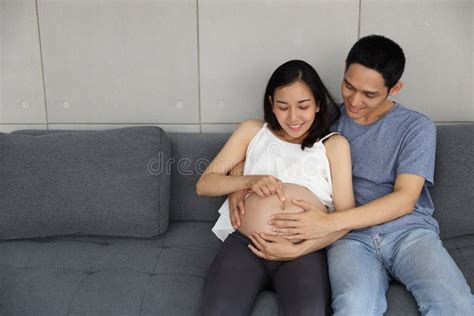 Young And Beautiful Pregnant Asian Woman In White Dress And Young Asian Husband Holding Hands On