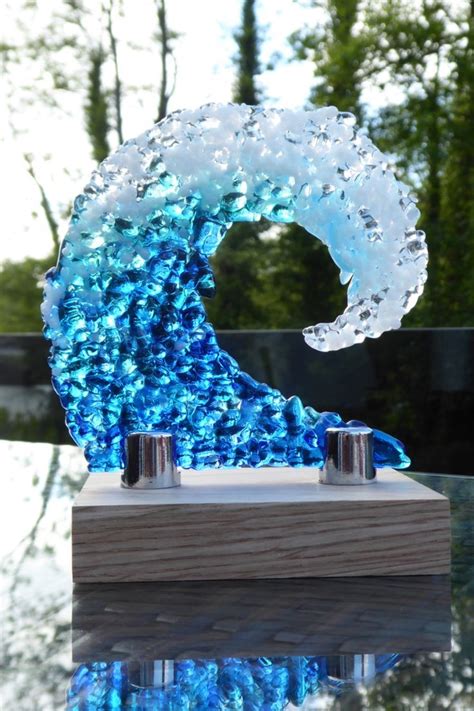 A Fused Glass Sculpture Of A Crashing Wave Made From Crushed Glass In Shades Of Blue Displayed