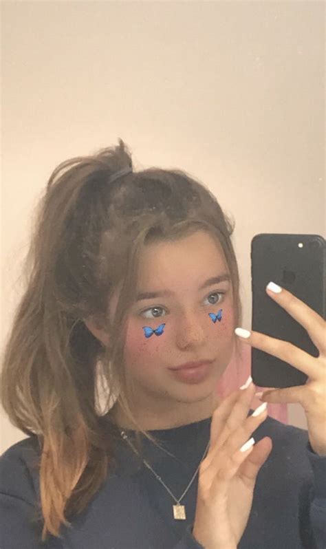 a woman taking a selfie with her phone and butterfly stickers on her face