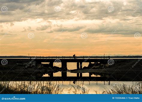 Man Bicycling Over A Railroad Trestle On Cloudy Sunset Evening Stock