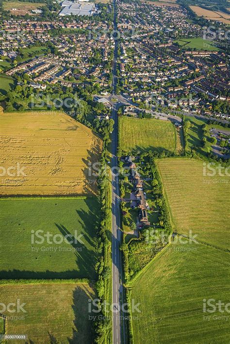Long Straight Road Through Green Fields To Suburbs Aerial View Stock