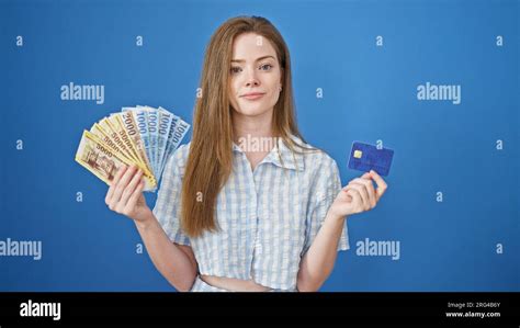 Young Blonde Woman Holding Hungary Forint Banknotes And Credit Card Over Isolated Blue