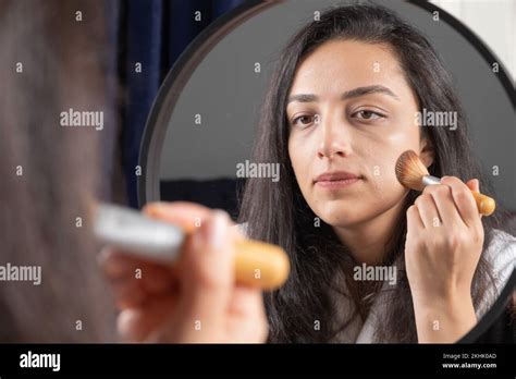 Young Beautiful Woman Applying Liquid Foundation On Her Face With Brush