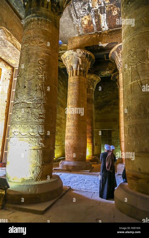 two arab men in traditional dress looking at the columns temple of edfu an egyptian temple