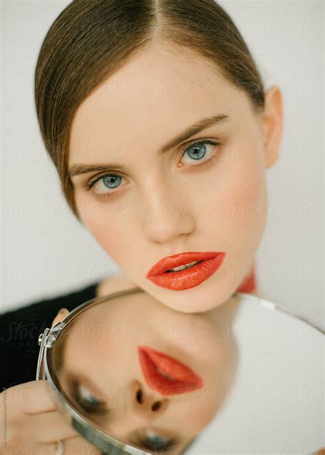 girl with perfect skin and red lips and her reflection by stocksy contributor julie meme