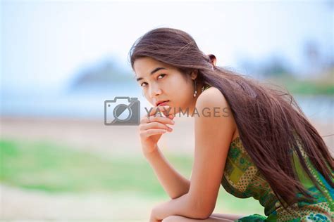 Beautiful Biracial Teen Girl Sitting At Tropical Beach Thinking By