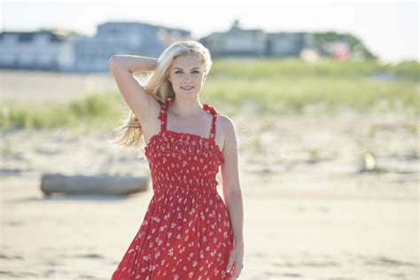 Stunning Young Blonde Woman Poses At Beach In Red Sundress Stock Image