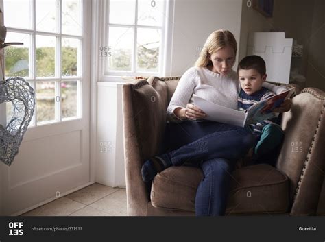 Mom Sitting In Chair At Home Reading Story To Her Son Stock Photo OFFSET