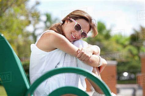 A Woman Sitting On A Park Bench Smiling At The Camera Stock Photo Dissolve