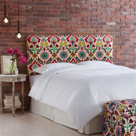 A Bed With White Sheets And Colorful Headboard Against A Brick Wall In A Bedroom