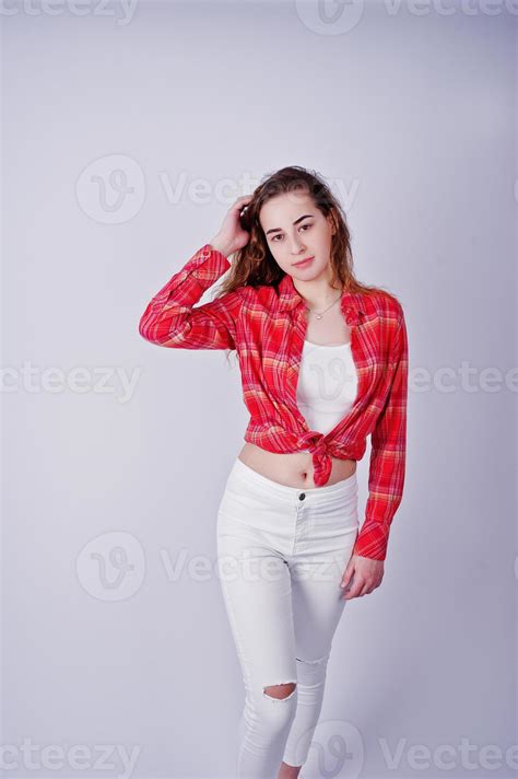Young Girl In Red Checked Shirt And White Pants Against White