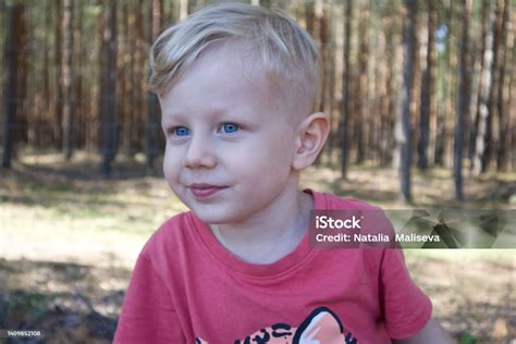 Seorang Anak Lakilaki Kecil Berambut Pirang Dan Bermata Biru Tersenyum Dengan Latar Belakang