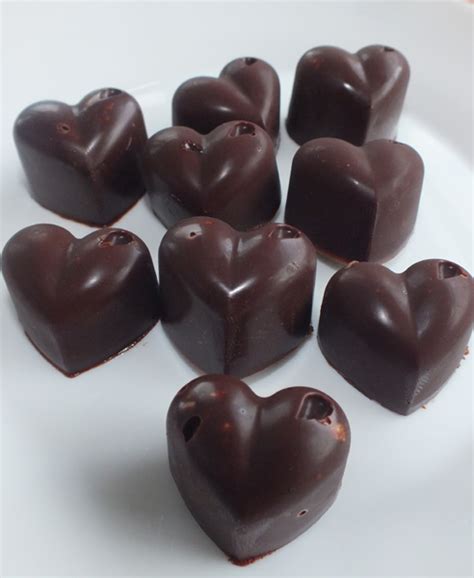Top view of heart shaped chocolate candy on round board with cutlery isolated on black. Heart Shaped Chilli Chocolates | HELLO!